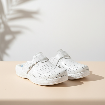 Pair of white clogs on a beige surface with a light background